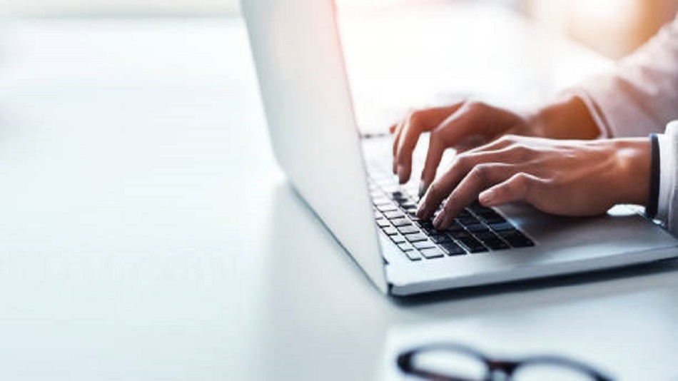 les mains d'une personne tapant sur le clavier d'un ordinateur - externalisation de la saisie de documents - Optiserv