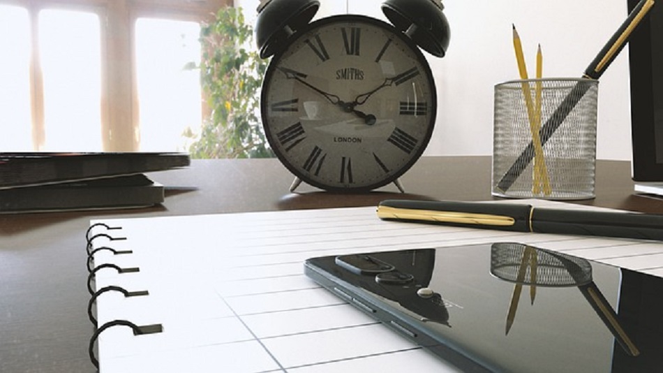 un horloge sur une table avec des outils de bureau - externaliser le standard téléphonique - optiserv