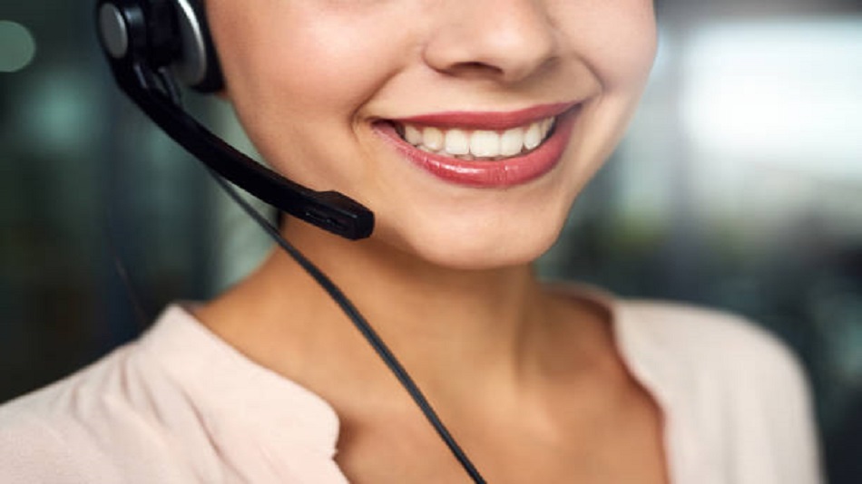 une femme souriante, avec un microcasque dans un centre d'appels - externaliser le service de permanence téléphonique - Optiserv