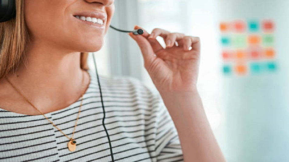 Femme d'affaires portant un casque souriant et parlant au microphone - externaliser les appels entrants - Optiserv 